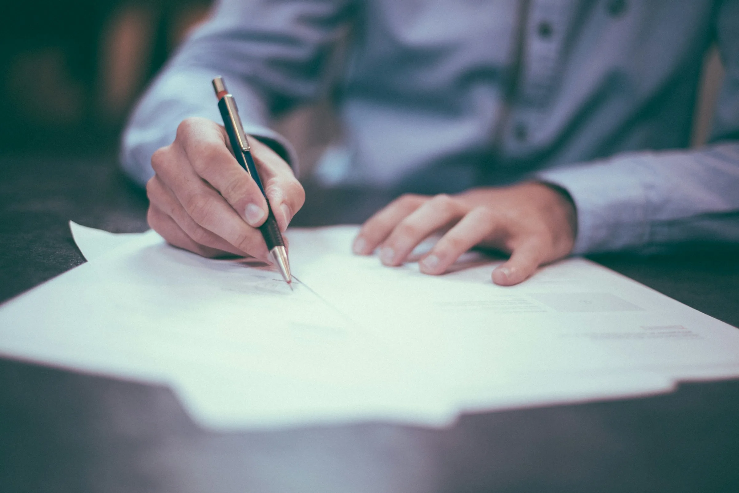 Hand signing a document with a pen